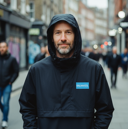 Man wearing a black jacket with a brand logo on a city street