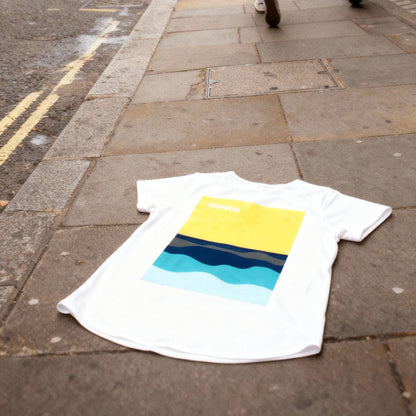 Person walking on a city street with a t-shirt featuring a colorful design on the ground.