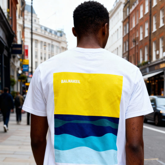 Person wearing a white t-shirt with colorful design on the back in an urban setting