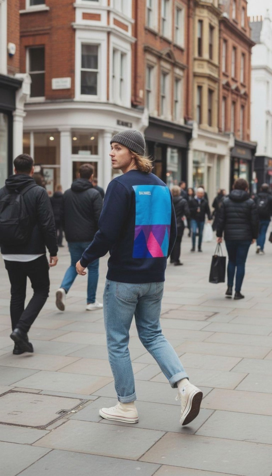 Man in city street wearing a navy blue sweat top with mountain design.